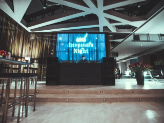 © Sergiu Andrés DJ performs at Investors Night on a stage with a blue-lit backdrop reading 'Investors Night'.