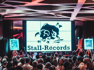 Palais_Wertheim_Konzert_Andreas-Gabalier-28 Large LED screen displaying the Stall-Records logo with a stylized bull, behind a crowded event hall.