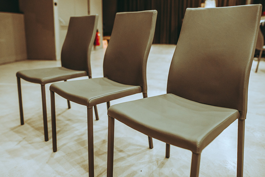 Three brown upholstered chairs lined up in a modern indoor room, viewed from the front-left angle.