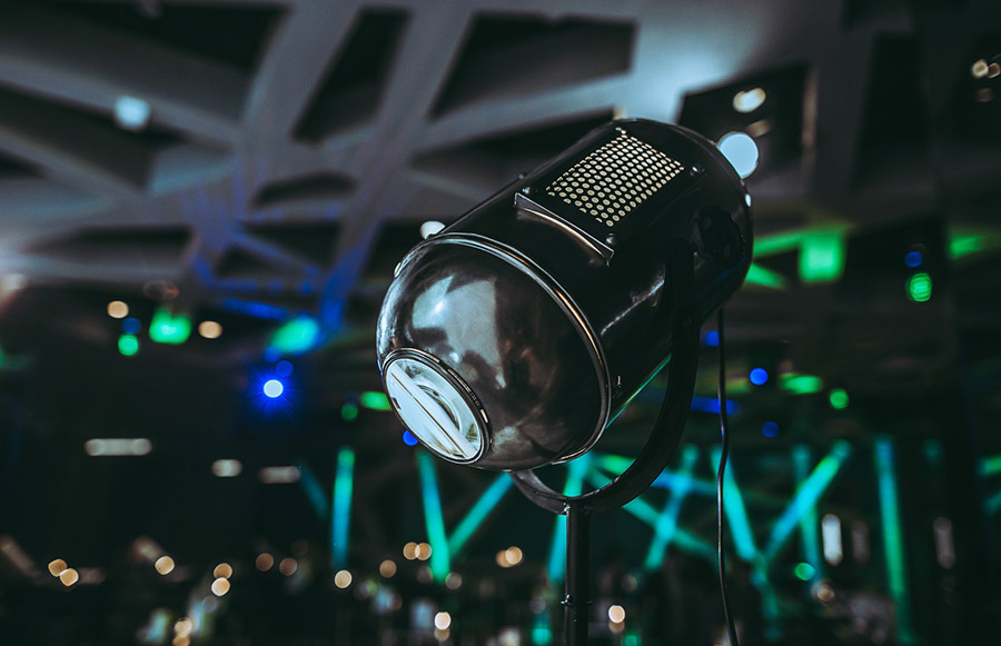 Retro studio microphone on a stand in a dim venue with green and blue stage lights